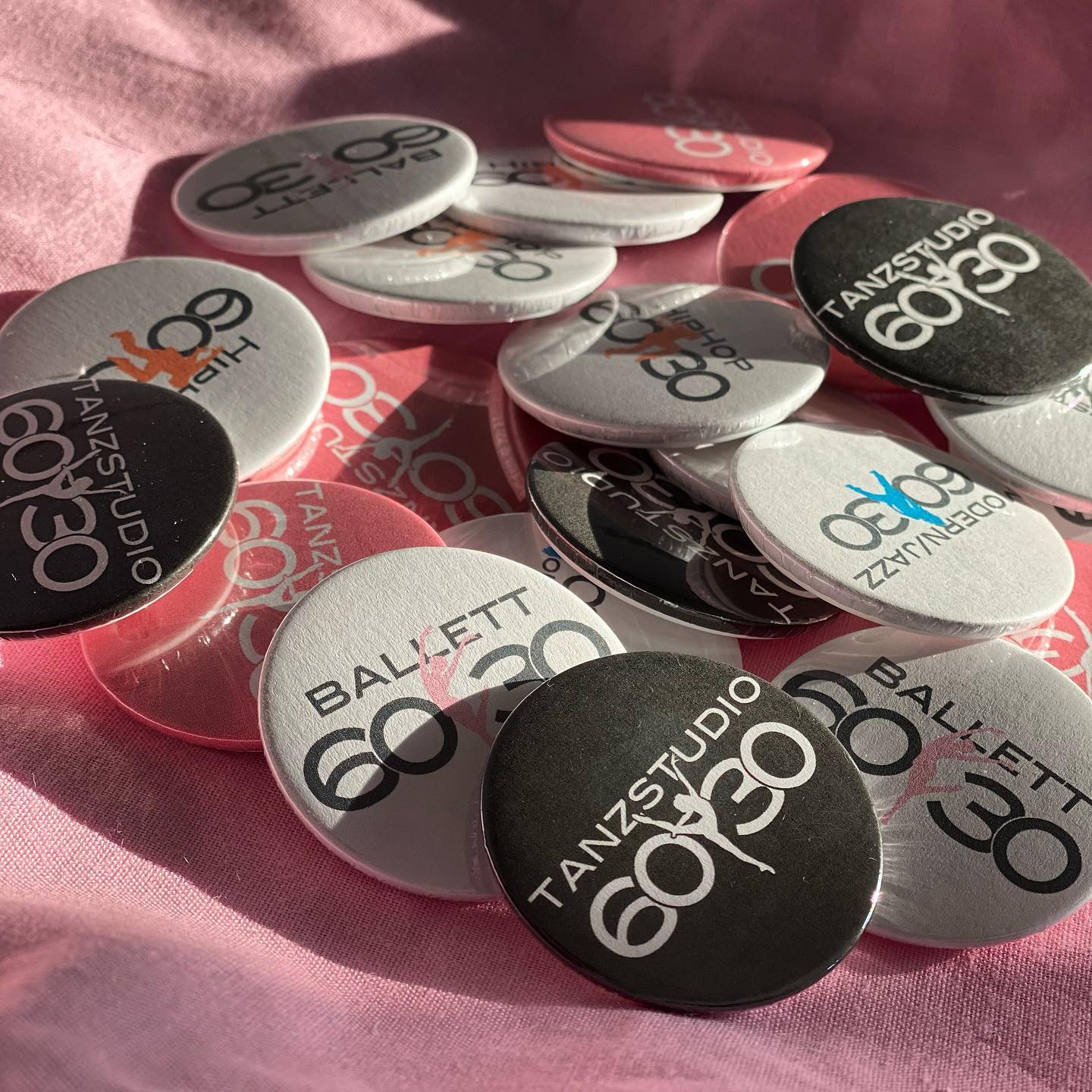 Anstecker mit dem Logo des Tanzstudios auf rosa Stoff